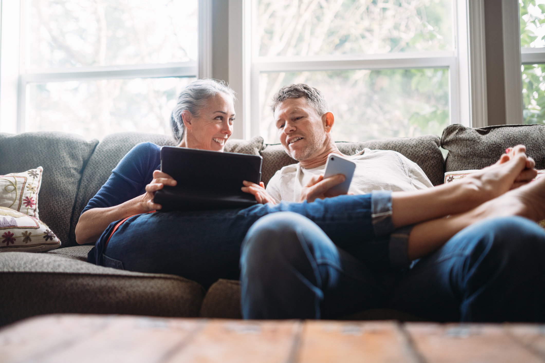 Une femme et un homme sont assis sur le canapé et regardent ensemble quelque chose sur leur ordinateur portable.