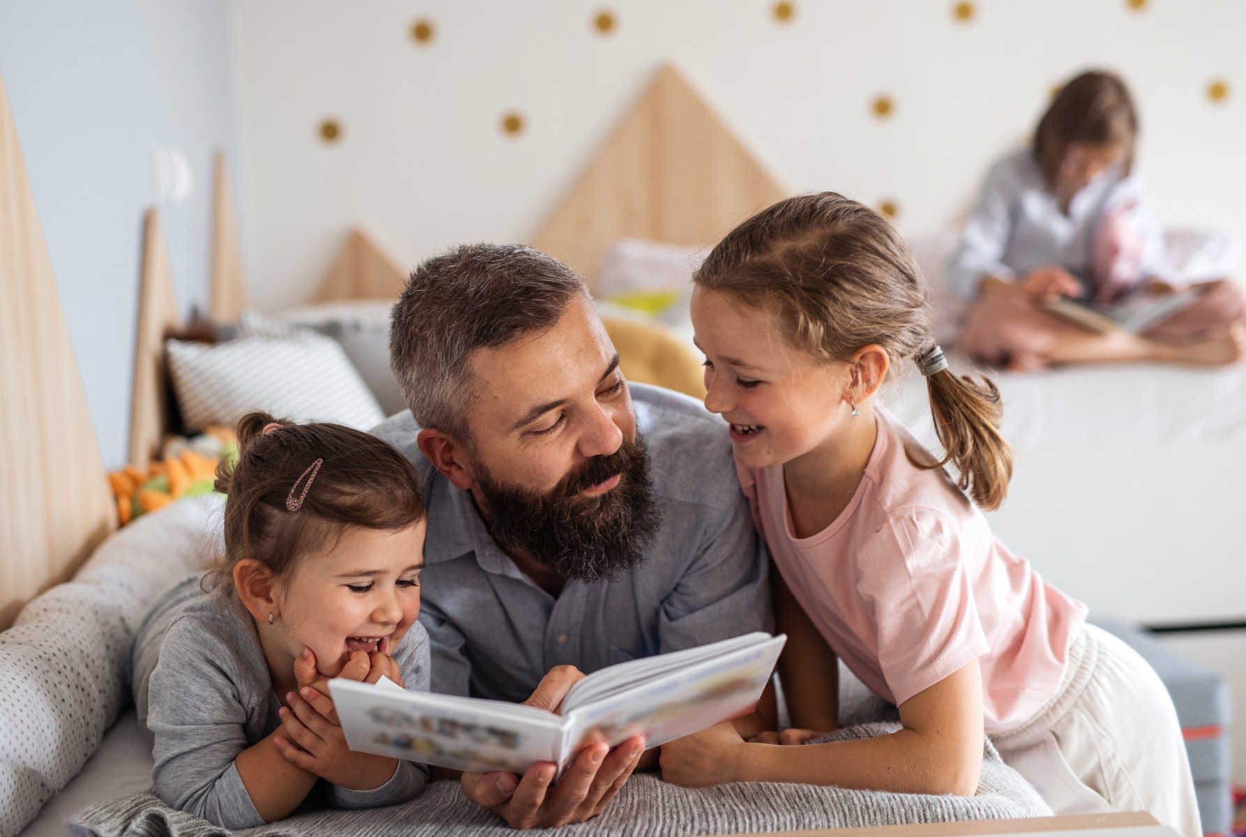 Un homme lit un livre pour enfants à ses deux filles.